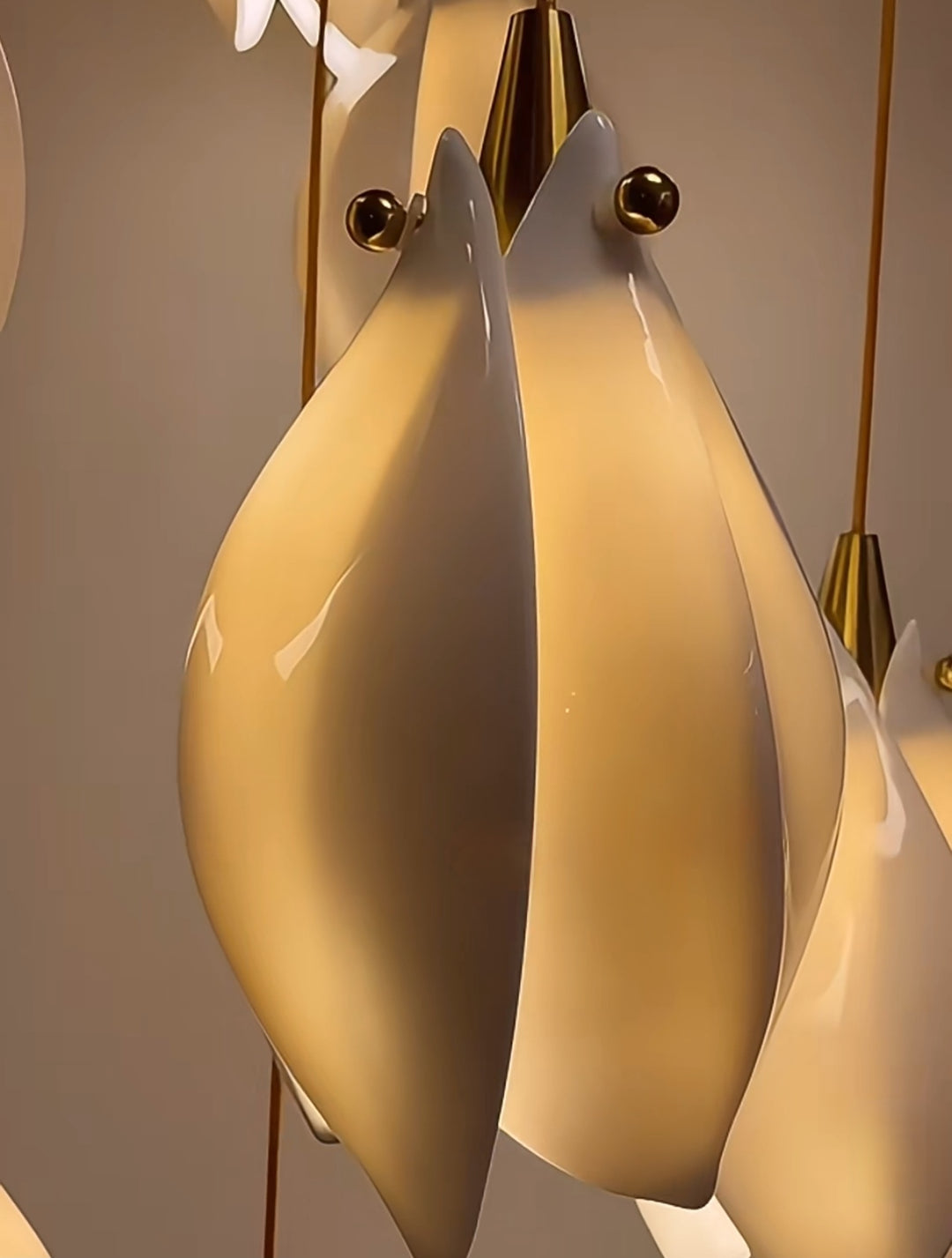 Close-up of a modern pendant light fixture with white lampshades and gold accents.
